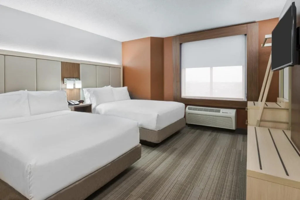 Room with two beds, wall-mounted TV and window at Holiday Inn Express Nearest Universal Orlando