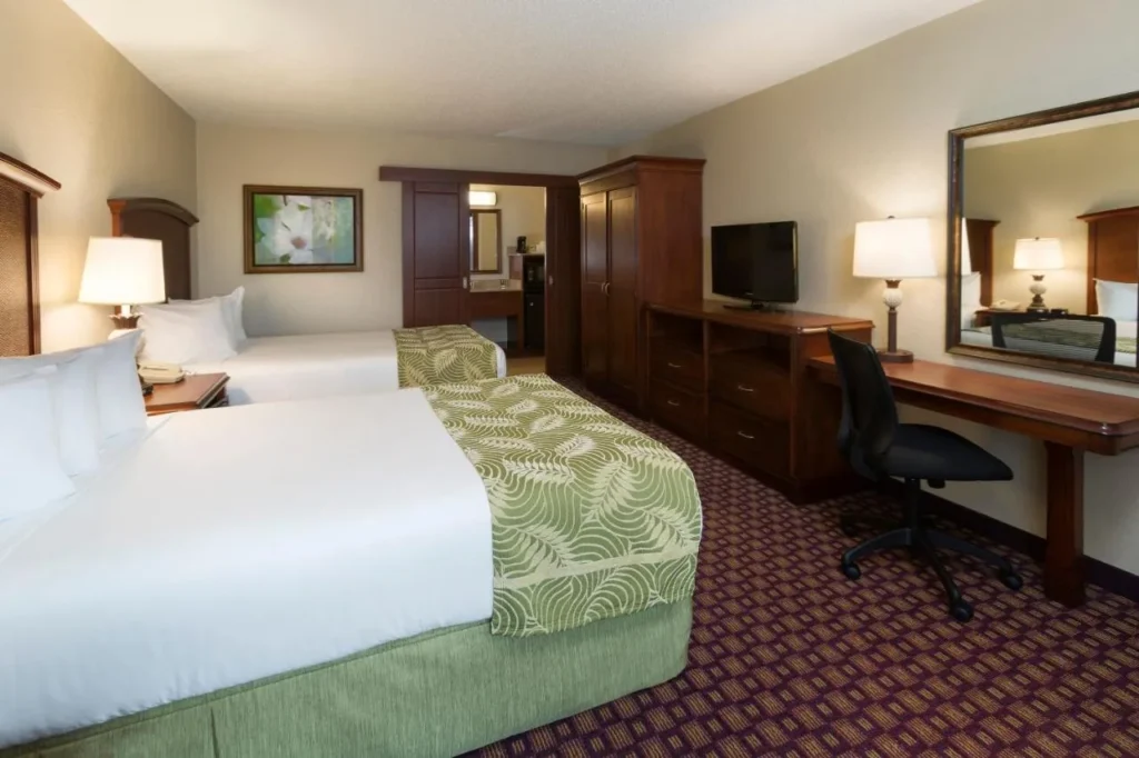 Habitación con dos camas dobles, escritorio, TV y armario en Rosen Inn Internacional