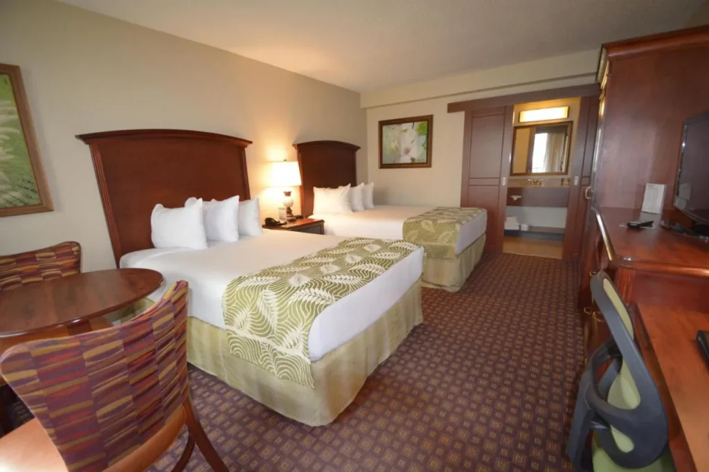 Room with two double beds, table and work desk at Rosen Inn Closest to Universal