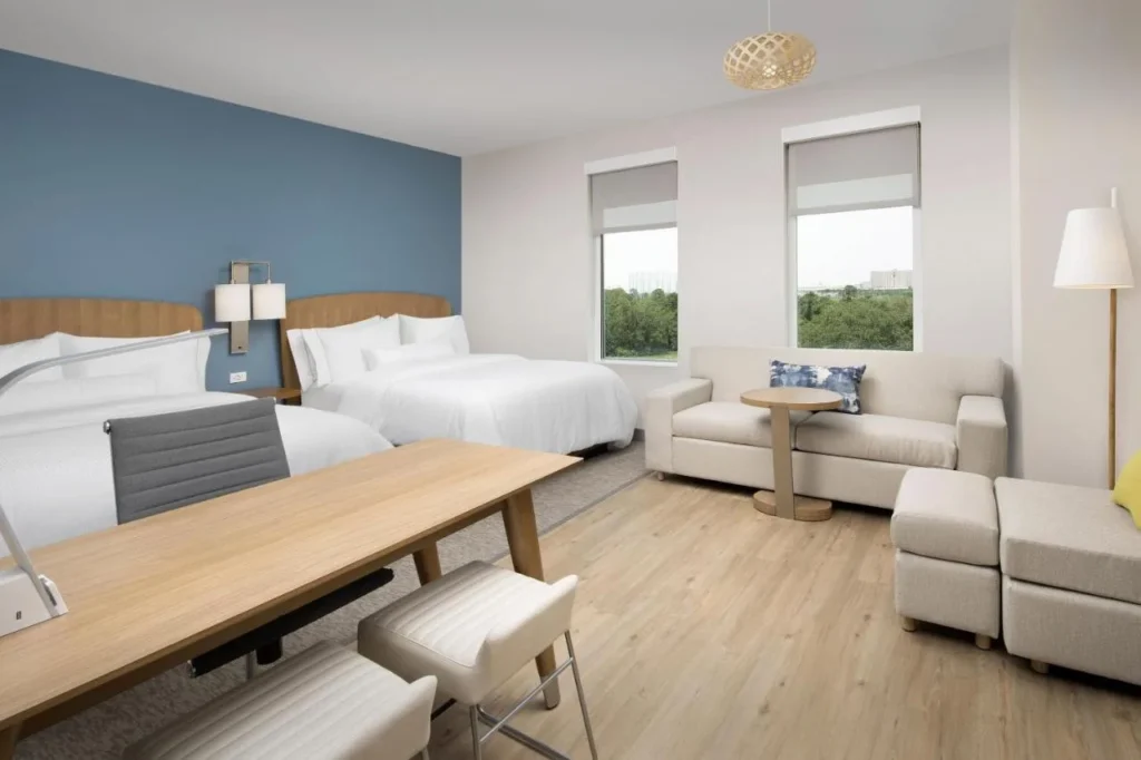 Habitaci&oacute;n con dos camas queen, un sof&aacute; y una mesa de trabajo en Element Orlando Universal Blvd.