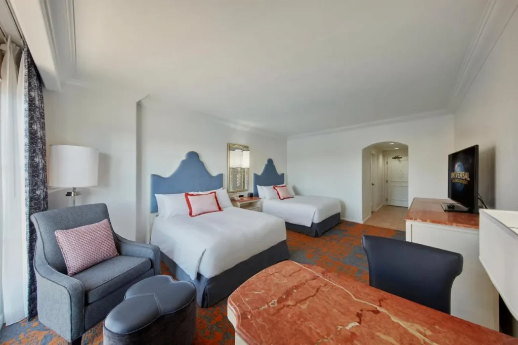 Room with two queen beds, an armchair and ottoman at Loews Portofino Bay Hotel