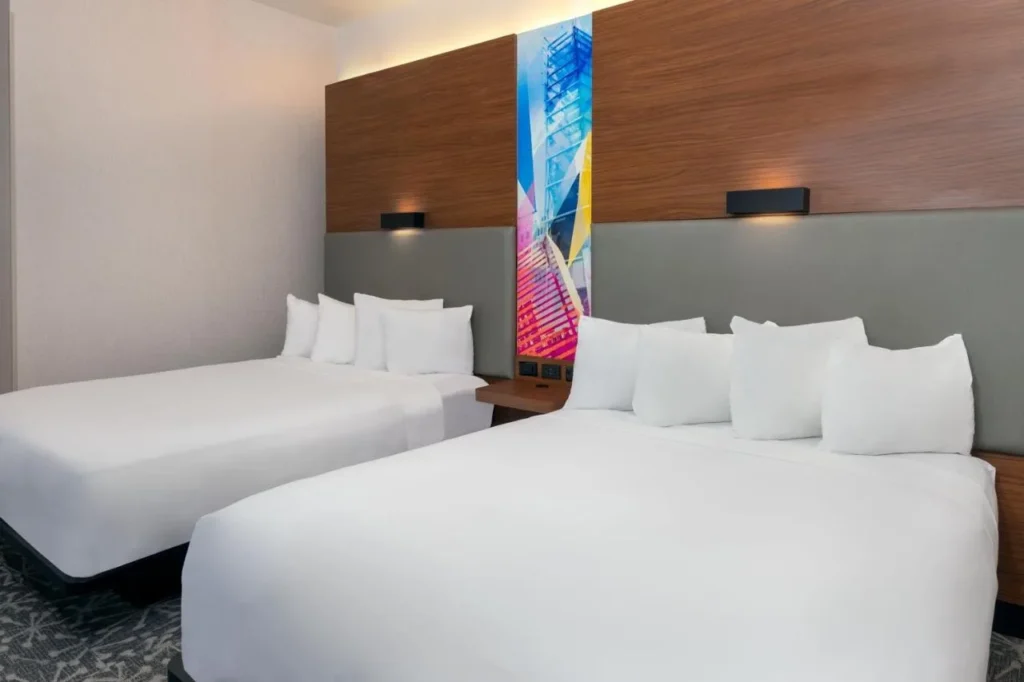 Habitación con dos camas queen y un colorido panel de arte en el Aloft Orlando Downtown