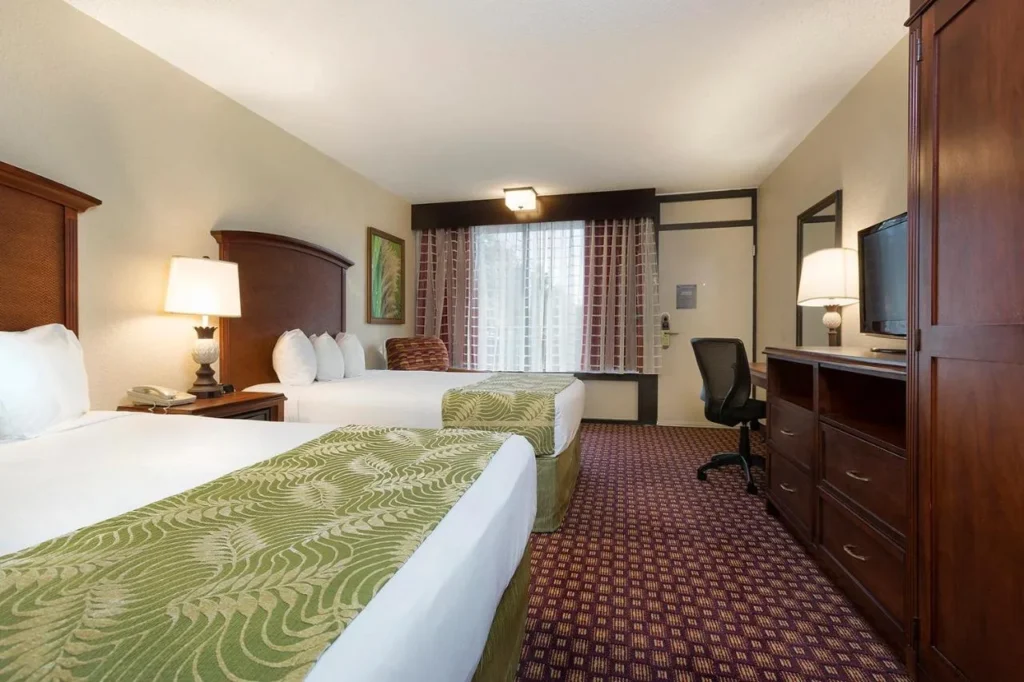Habitaci&oacute;n con dos camas queen, escritorio y c&oacute;moda en Rosen Inn at Pointe Orlando