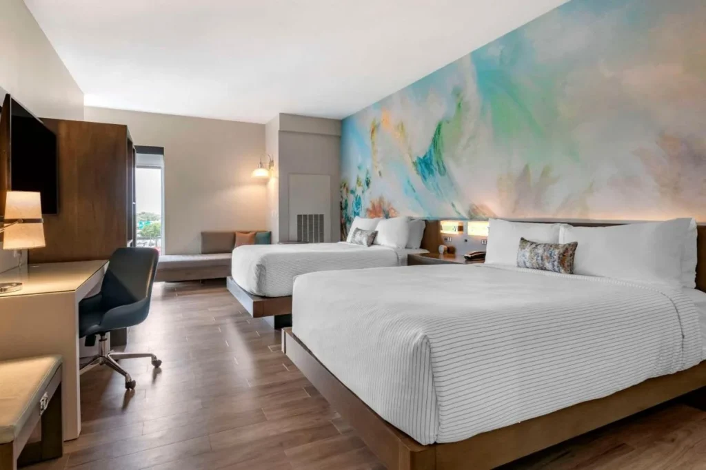 Habitaci&oacute;n con dos camas queen, escritorio y mural pintado en el Cambria Hotel Orlando Airport