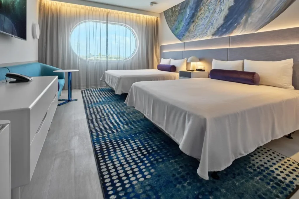 Room with two queen beds, planet mural and oval window at Universal Terra Luna Resort