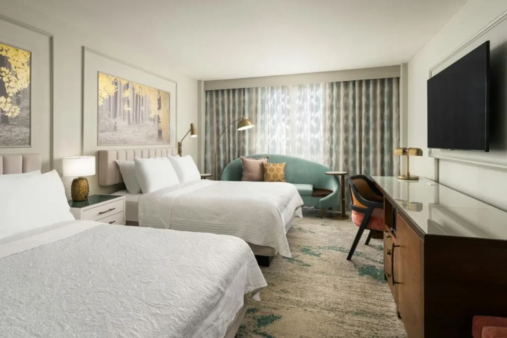 Room with two queen beds, teal sofa and gold forest artwork at Castle Hotel Orlando
