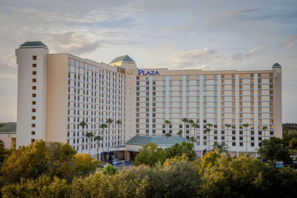 Rosen Plaza Hotel tower with its Rosen Plaza sign above trees in soft evening light