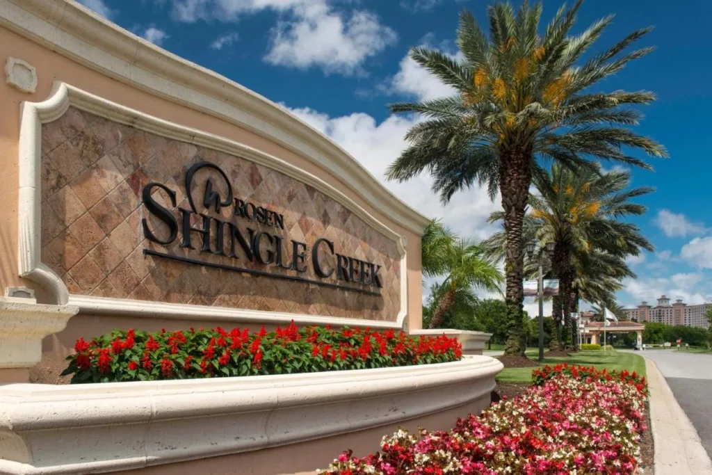 Rosen Shingle Creek entrance sign with red flower beds, palm trees and the hotel beyond