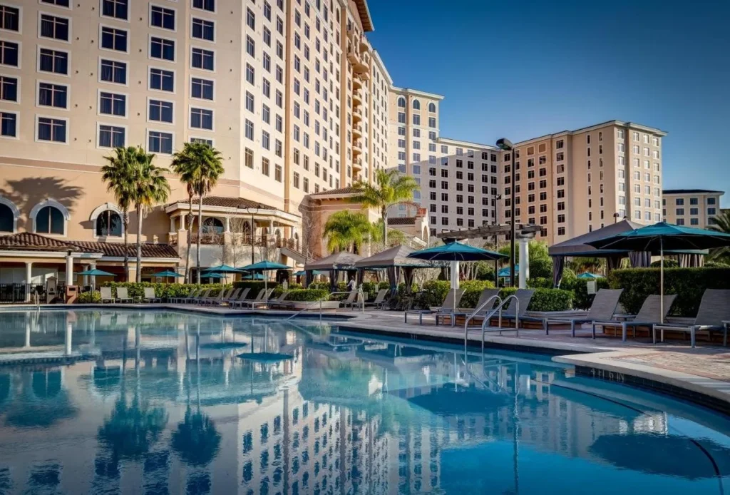 Rosen Shingle Creek pool deck with cabanas, teal umbrellas and the hotel tower behind