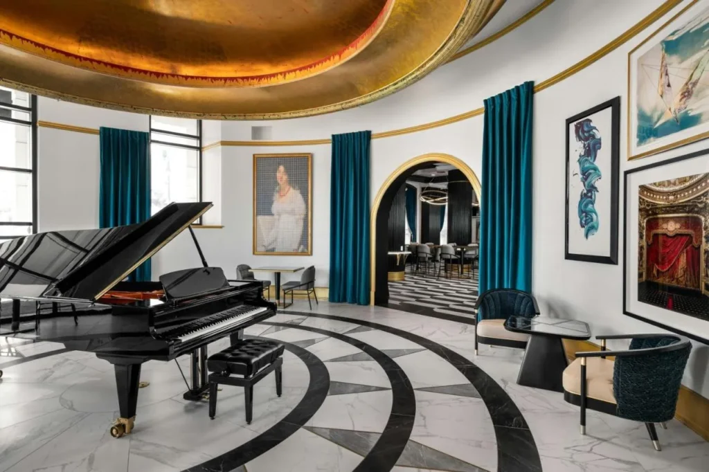 Rotunda lounge with a grand piano, gold dome ceiling and framed art at Hotel Beauden