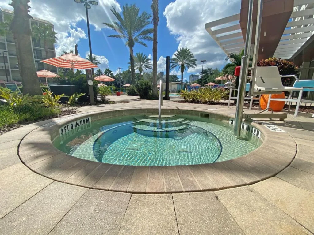 Bañera de hidromasaje redonda en la cubierta de la piscina bordeada de palmeras en Holiday Inn Orlando Disney Springs