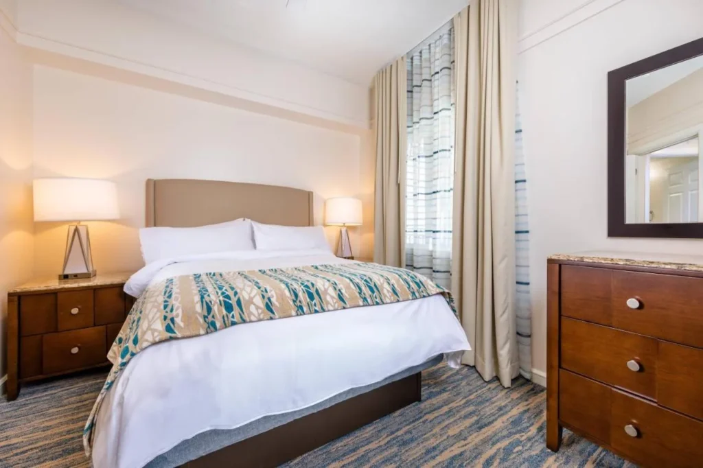 Segundo dormitorio con una cama, l&aacute;mparas de noche, una c&oacute;moda y ventana con cortinas en Marriott's Cypress Harbour