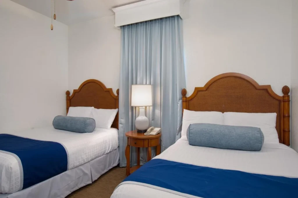 Second bedroom with two beds and blue bolster pillows at Lake Buena Vista Resort Village