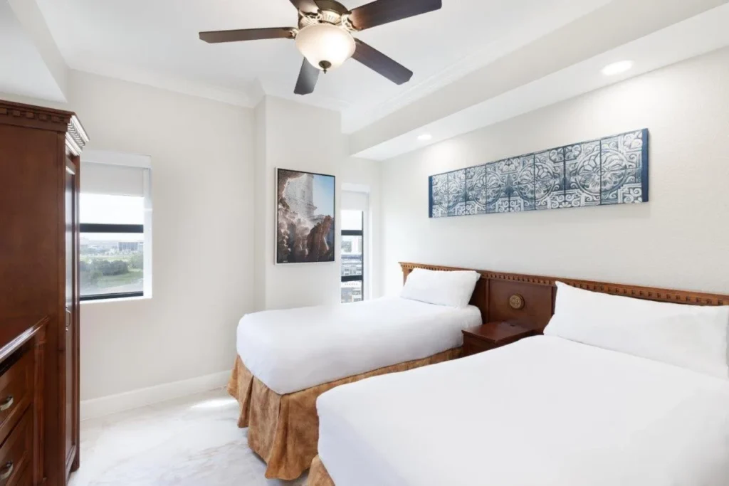 Second bedroom with two twin beds, ceiling fan and city-view window at Westgate Palace
