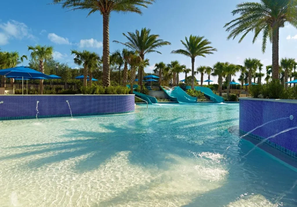 Piscina poco profunda de entrada cero con chorros de fuente y tres toboganes en Omni Orlando Resort at ChampionsGate