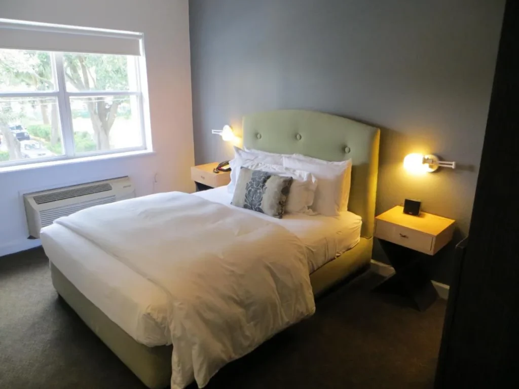 Habitaci&oacute;n sencilla en el EO Inn con cama queen, cabecero tapizado y l&aacute;mparas de pared