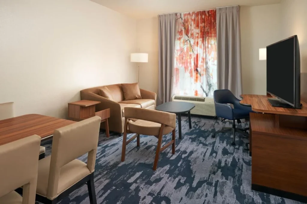 Zona de estar con sofá, mesa de comedor y TV en el Fairfield Inn & Suites Orlando International Drive