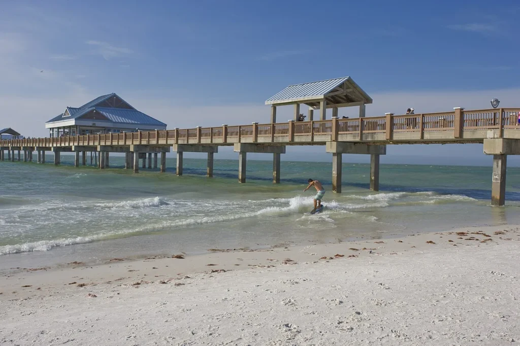 Skimboarder en el Golfo surf al lado del muelle largo 60 en Clearwater Beach con arena blanca