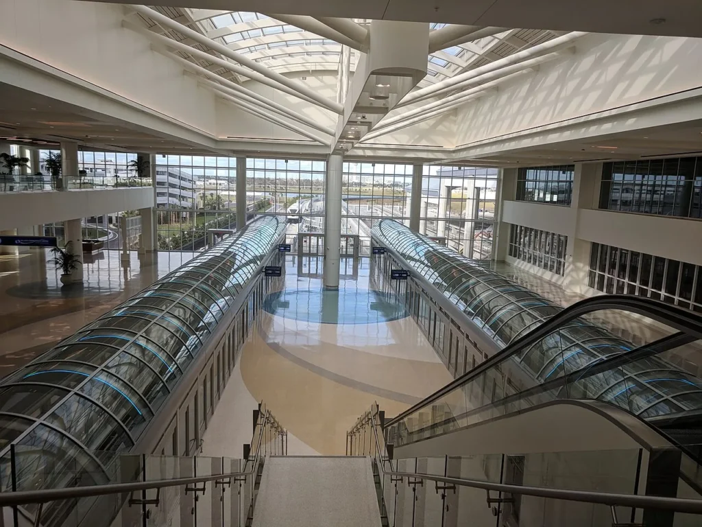 Sala Skylit con escaleras mecánicas y tubos de vidrio para personas en la Terminal Intermodal del Aeropuerto Internacional de Orlando