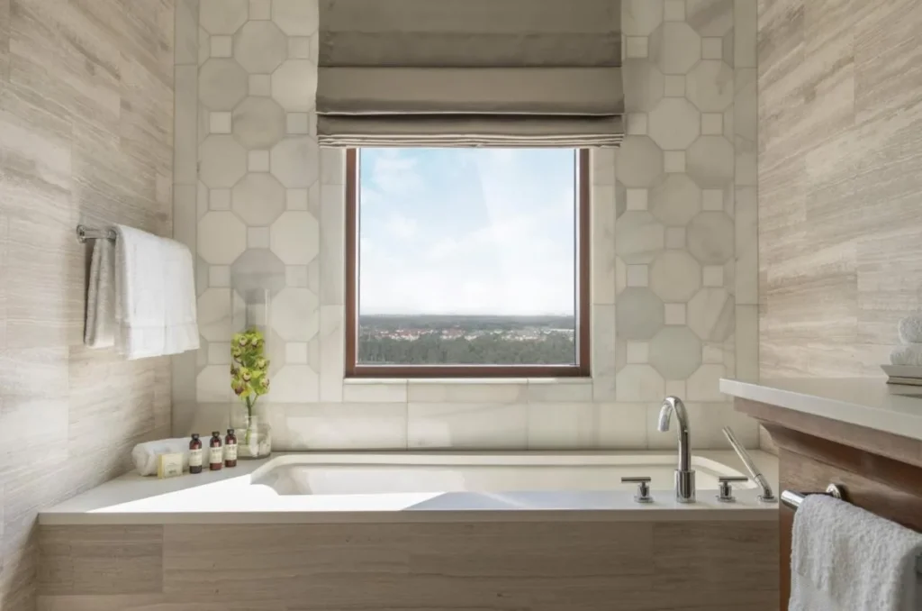 Bañera de hidromasaje bajo una ventana con vistas a los árboles en un cuarto de baño Four Seasons Resort Orlando