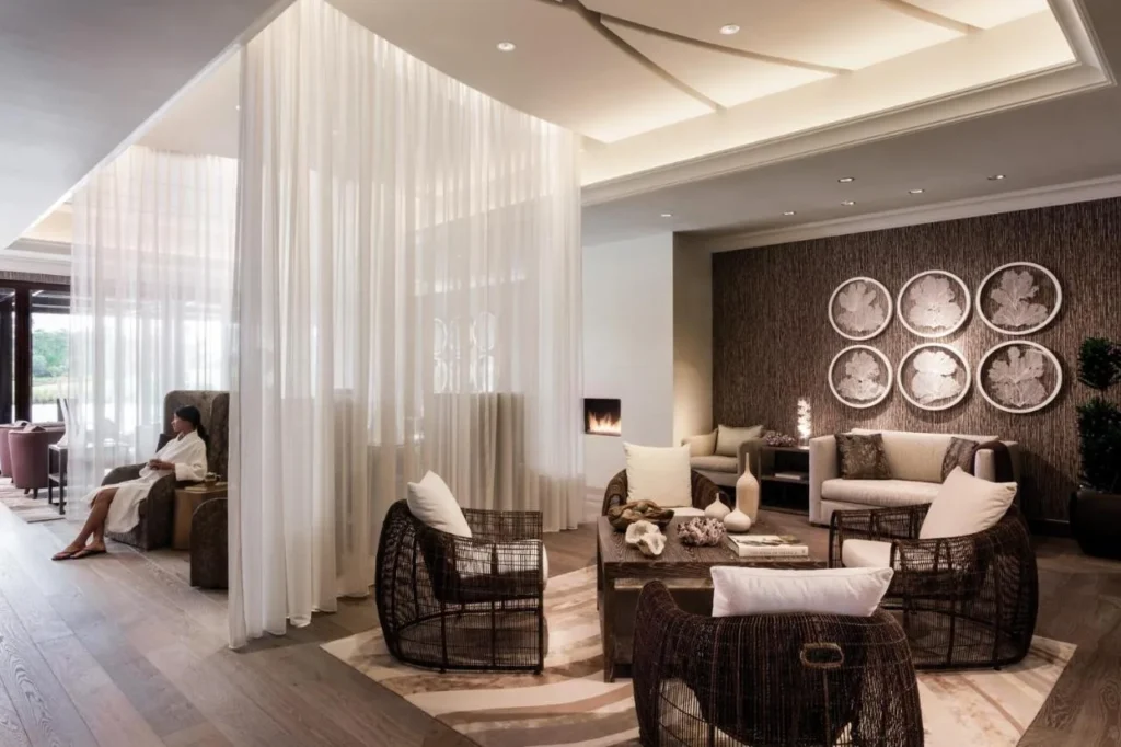 Spa relaxation lounge with sheer curtains, wicker chairs and a fireplace at Four Seasons Resort Orlando