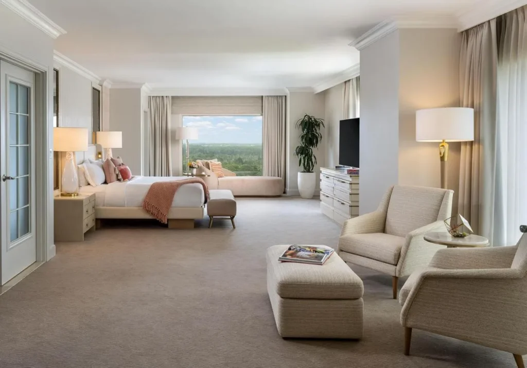 Spacious suite bedroom with armchairs, a daybed and a forest view at Waldorf Astoria Orlando
