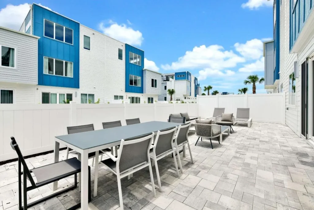Spectrum Resort Orlando townhome patio with long dining table and loungers beside blue and white homes