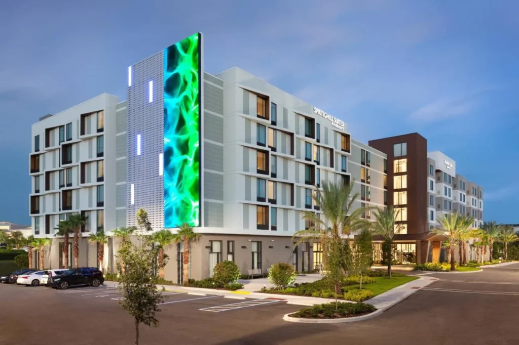 SpringHill Suites Orlando at Millenia exterior con un panel de pared iluminado, palmeras y estacionamiento