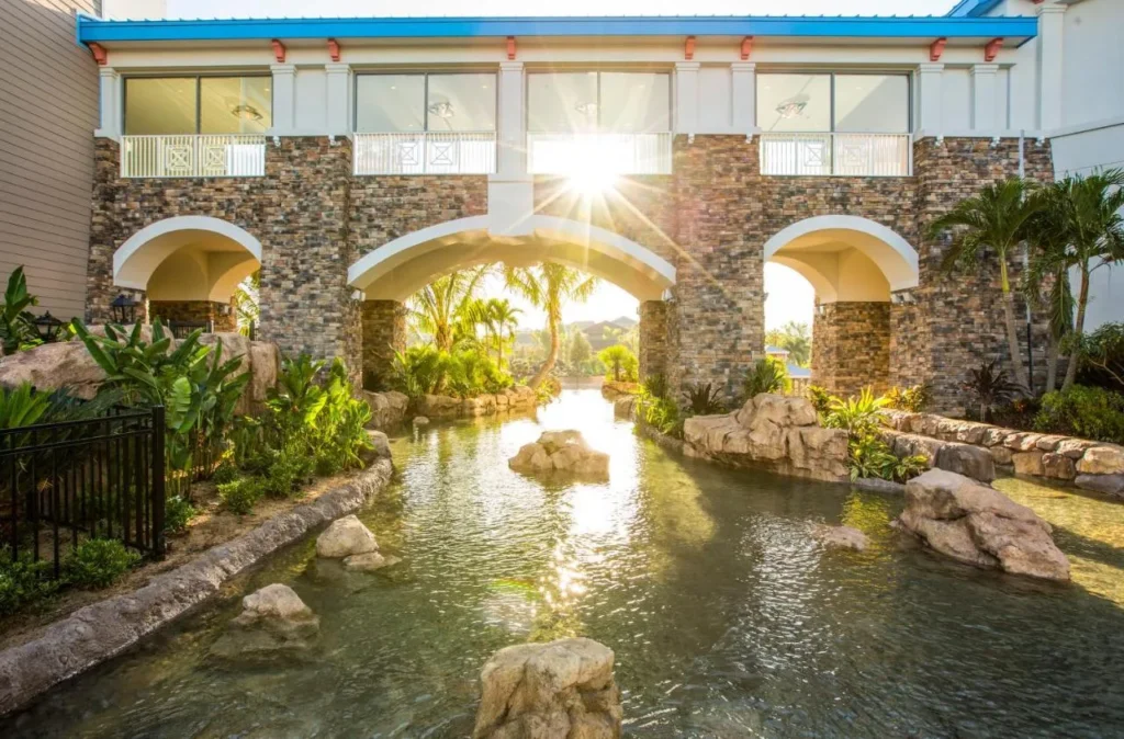 Stone archway over a rock-lined waterway and tropical plants at Loews Sapphire Falls Resort