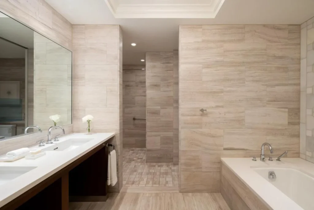 Stone-tiled bathroom with double vanity, soaking tub and walk-in shower at Four Seasons Resort Orlando