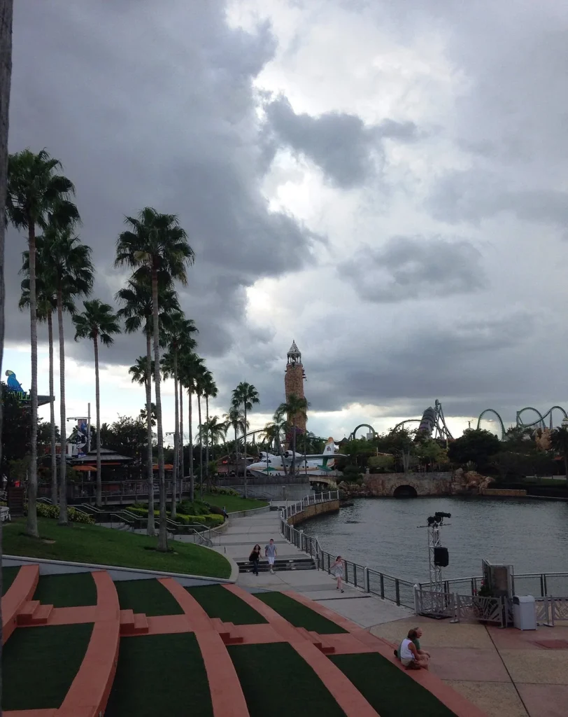 Storm clouds gathering over the Islands of Adventure lighthouse and Hulk coaster, seen from CityWalk