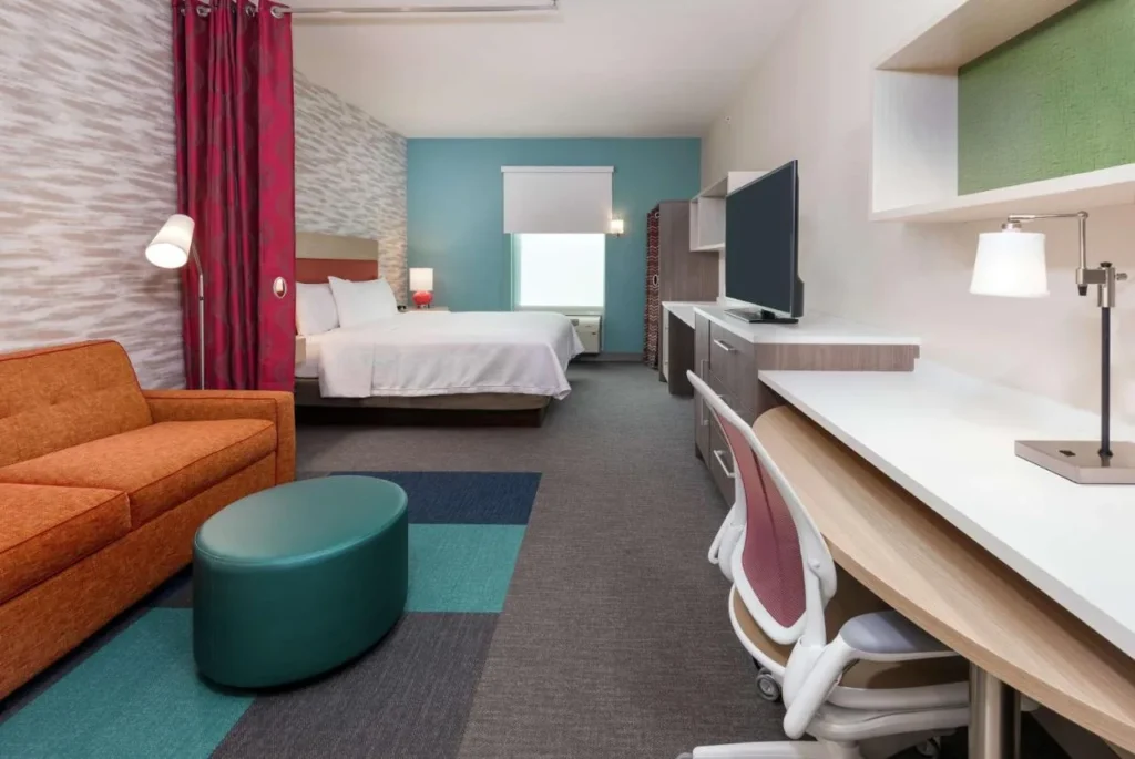 Suite estudio con cama king size, sofá naranja y escritorio en Home2 Suites Orlando Near UCF