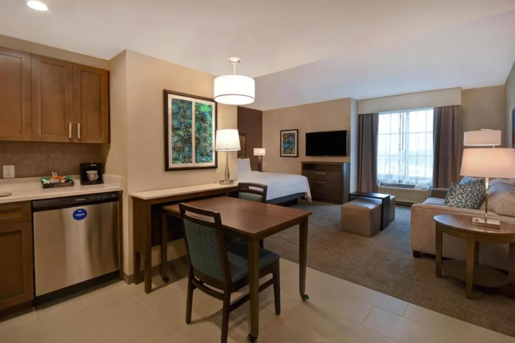 Studio suite with kitchen, dishwasher, dining table, bed and sofa at Homewood Suites Flamingo Crossings
