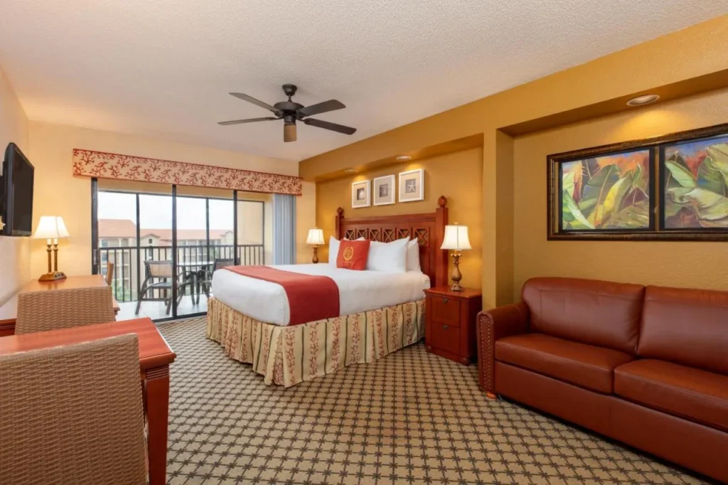 Studio villa with a king bed, leather sofa and balcony door at Westgate Lakes
