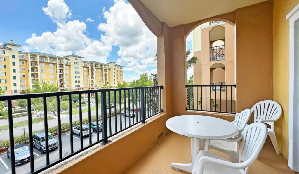 Suite con balcón con mesa y sillas frente a las torres amarillas de Lake Buena Vista Resort Village & Spa