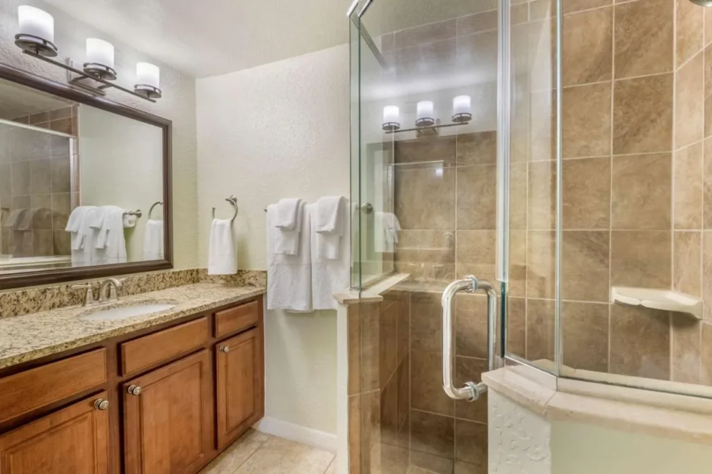 Ba&ntilde;o de la suite con una vanidad de granito y ducha de azulejos de vidrio en Mystic Dunes Resort