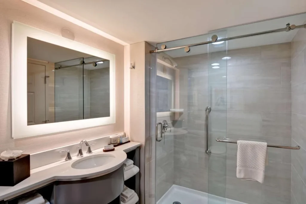 Suite bathroom with lit mirror and glass walk-in shower at Embassy Suites Orlando Downtown