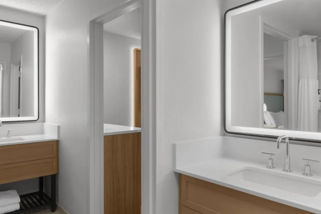 Ba&ntilde;o de la suite con dos lavabos y espejos iluminados en Embassy Suites Orlando ICON Park