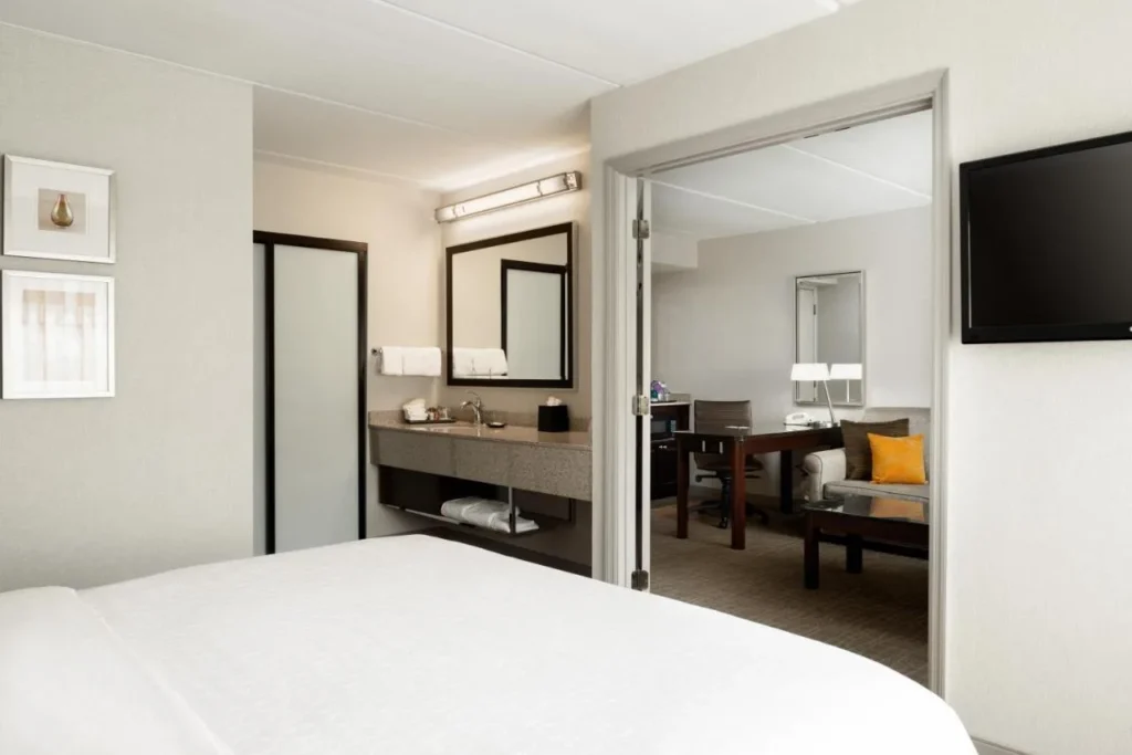 Dormitorio de la suite que se abre a una sala de estar separada con sof&aacute; en Sheraton Suites Orlando Airport