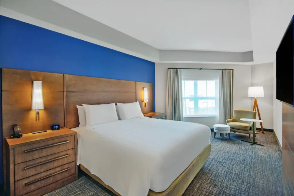 Dormitorio de la suite con cama king y sillón en el Residence Inn Orlando at Flamingo Crossings