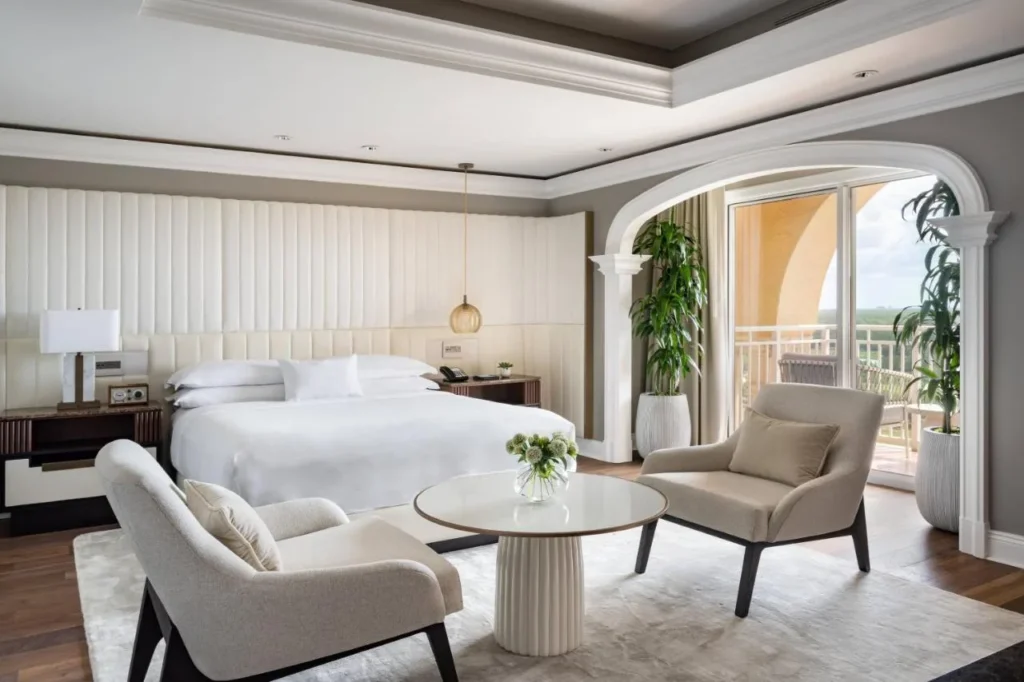 Habitación suite con cama king size, sillones y puertas de balcón arqueadas en The Ritz-Carlton Orlando