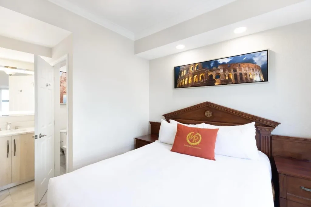 Suite bedroom with a large bed, Colosseum print and en suite door at Westgate Palace