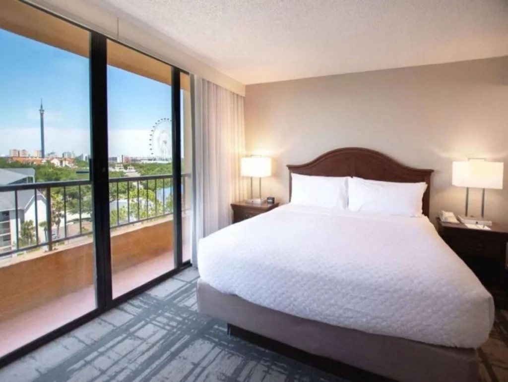 Suite bedroom with balcony and a view of The Wheel at Embassy Suites Convention Center