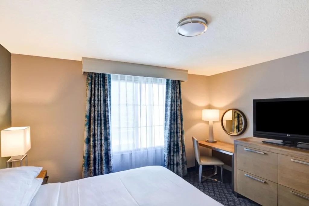 Suite bedroom with desk, TV and window at Embassy Suites by Hilton Orlando Downtown