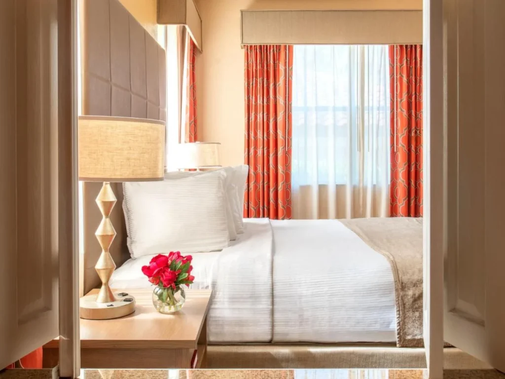 Suite bedroom with orange curtains and flowers on the nightstand at Floridays Resort Orlando