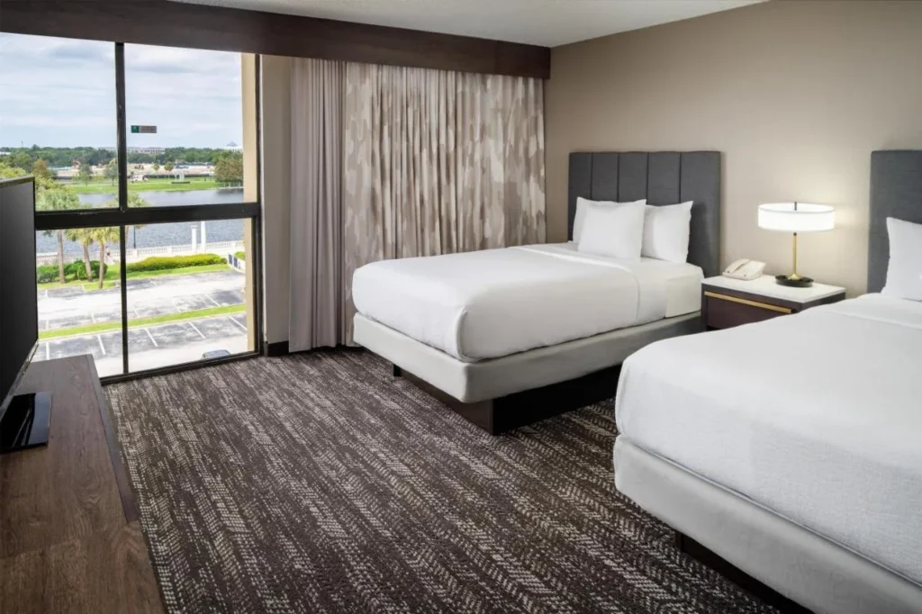Suite bedroom with two beds and a window overlooking the lake at Embassy Suites Orlando North