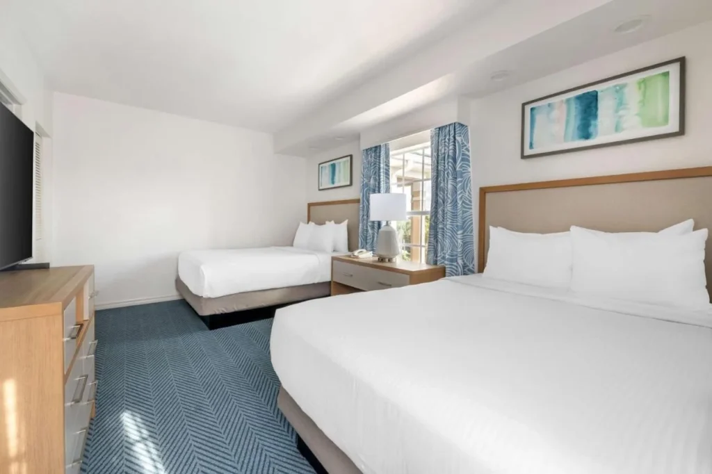 Habitaci&oacute;n suite con dos camas, cortinas azules y una c&oacute;moda en Mystic Dunes Resort