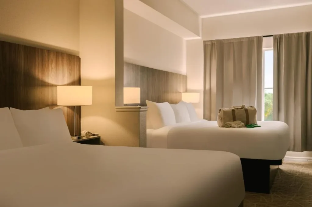 Suite bedroom with two large beds and a curtained window at The Point Hotel & Suites