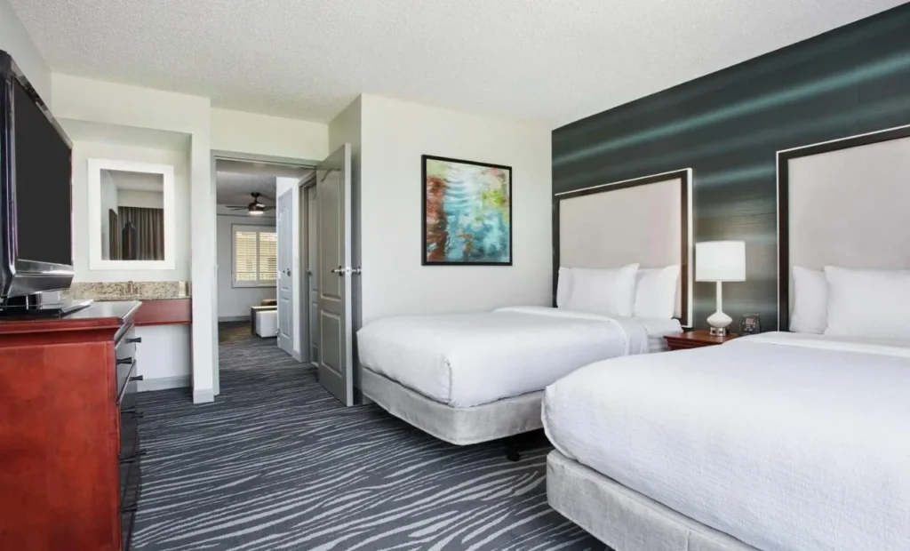 Suite bedroom with two queen beds and a dark accent wall at Embassy Suites Orlando Airport