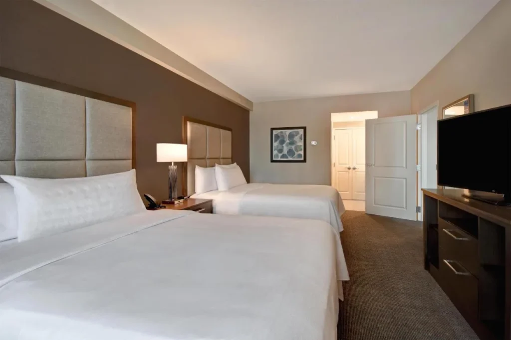 Habitación Suite con dos camas queen y TV en el Homewood Suites Flamingo Crossings